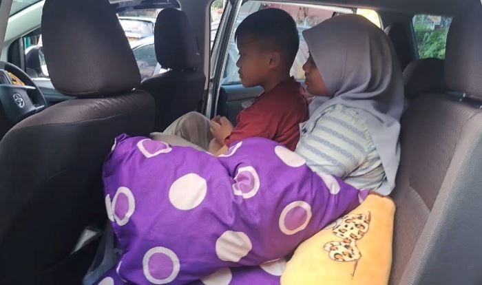 LEGA: Arsya dipangku kakaknya dalam mobil, setelah hamper satu jam terkunci dalam kondisi tertidur pulas. (foto: Moch. Chariris)