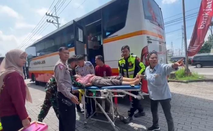DIEVAKUASI: Petugas mengevakuasi penumpang bus PO Harapan Jaya yang pingsan, di Rest Area Gunung Gedangan, Kecamatan Magersari, Kota Mojokerto. (foto: Moch. Chariris)