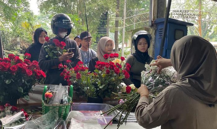 DIGEMARI: Lapak bunga segar milik pasangan Amel dan Udi Bagus, di kawasan objek wisata Sendi, Pacet, Mojokerto jadi jujukan pasangan kekasih membeli bunga mawar. (foto: Moch. Chariris)
