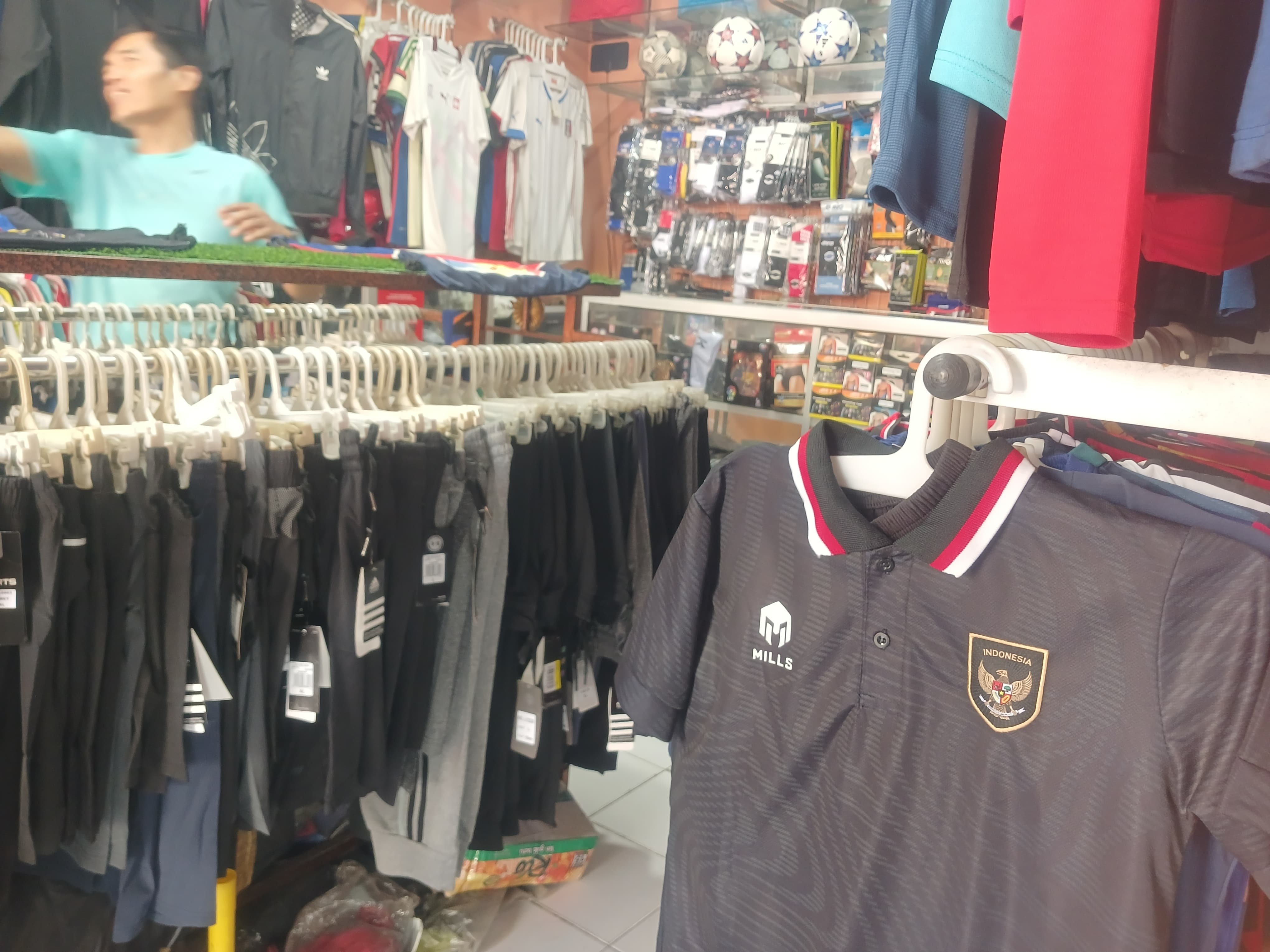KECELE: Dua pegawai dinas di Kota Mojokerto memilah baju klub sepak bola setelah kehabisan jersey timnas di toko kostum olahraga Vandist Sport, Jalan Pahlawan, Kota Mojokerto, Senin (29/4) siang.