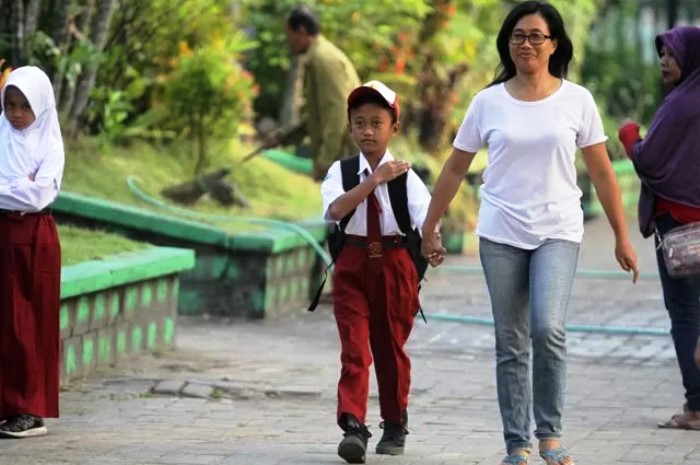 ASUH: Salah satu wali murid tampak menggandeng anaknya berangkat sekolah saat masa masuk sekolah  perdana.