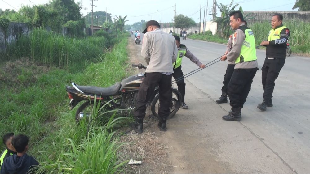 DIEVAKUASI: Petugas mengevakuasi motor korban yang terperosok di selokan sekitar lokasi, Senin (6/5).