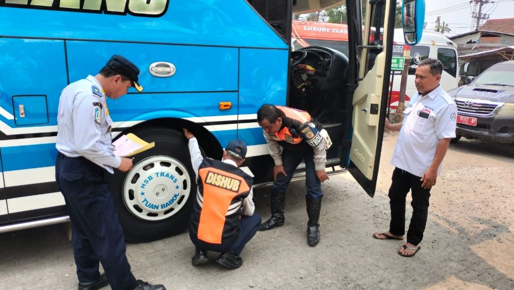 TINDAK TEGAS: Petugas UPT P3 LLAJ Dishub Jatim memeriksa kelengkapan surat bus pariwisata di halaman parkir wisata religi Troloyo, Trowulan kemarin.