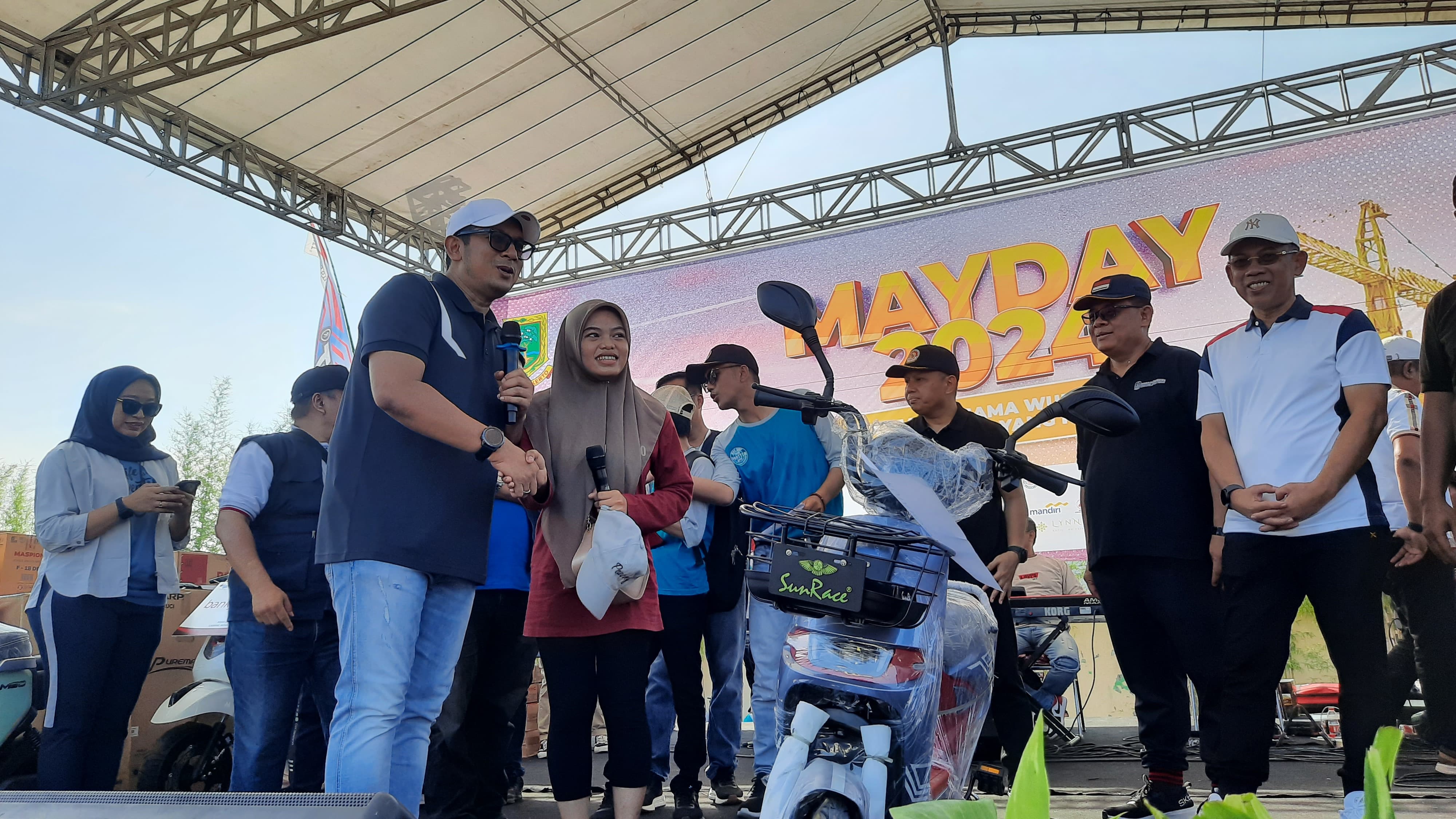 APRESIASI: Pj Wali Kota Mojokerto Moh. Ali Kuncoro memberikan doorprize berupa sepeda listrik kepada salah satu peserta jalan sehat memperingati May Day 2024, Minggu (12/5).