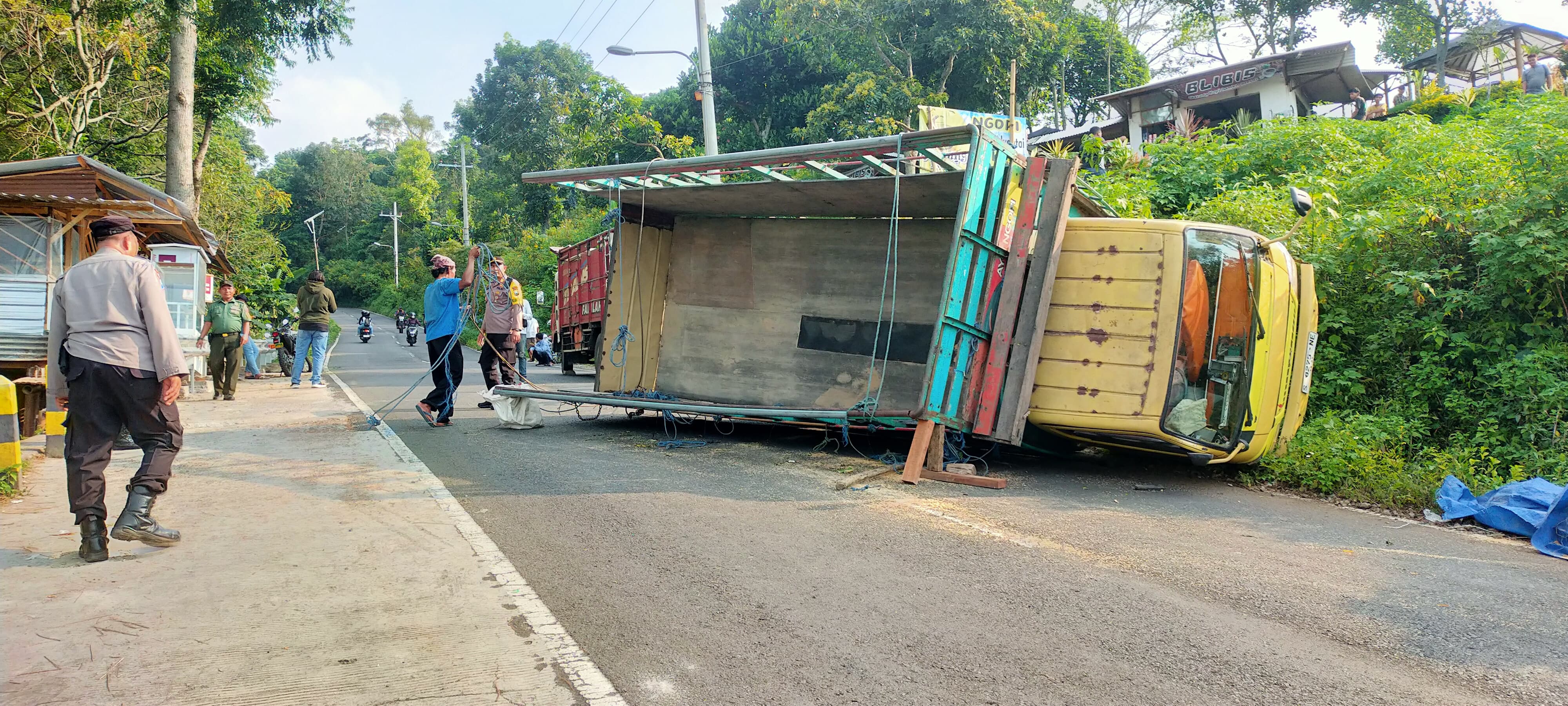 DIEVAKUASI: Truk engkel nopol S 8275 NE terguling di turunan AMD Jalur Pacet - Cangar, Desa/Kecamatan Pacet, Mojokerto, dievakuasi secara manual.