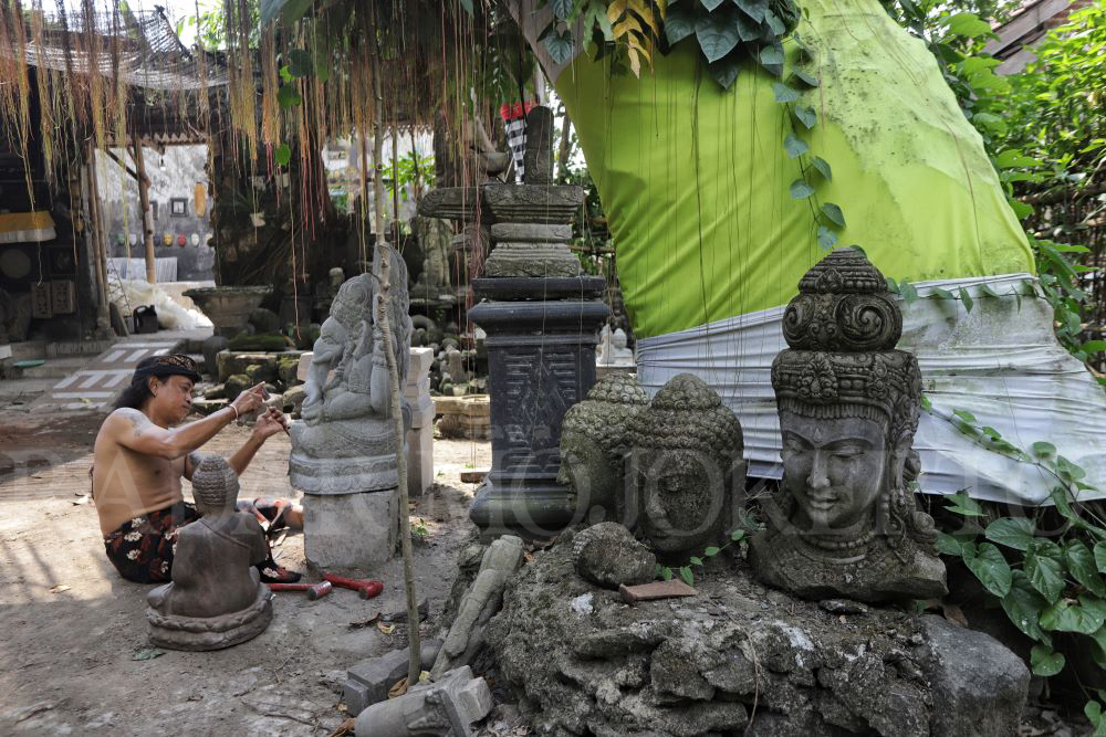 TELATEN: Perajin di Trowulan, Kabupaten Mojokerto, sedang memahat patung.