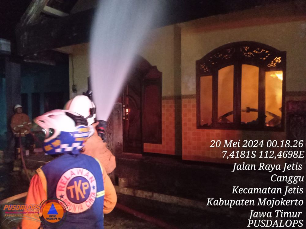 BERJIBAKU: Petugas pemadam kebakaran menyemprotkan air ke dalam rumah Choirul Anam, warga Dusun Pelabuhan, Desa Canggu, Kecamatan Jetis, Kabupaten Mojokerto yang terbakar, Minggu (19/5).