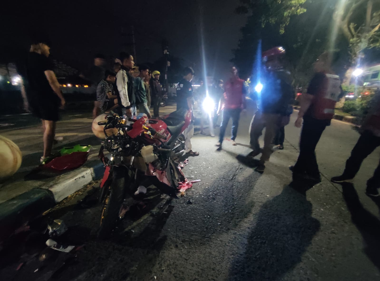HANCUR: Sepeda motor Ninja merah yang terlibat kecelakaan di putar balik Jalan RA Basuni, Kecamatan Sooko, Kabupaten Mojokerto depan kantor PN Mojokerto diamankan petugas dan relawan, Jumat (31/5)