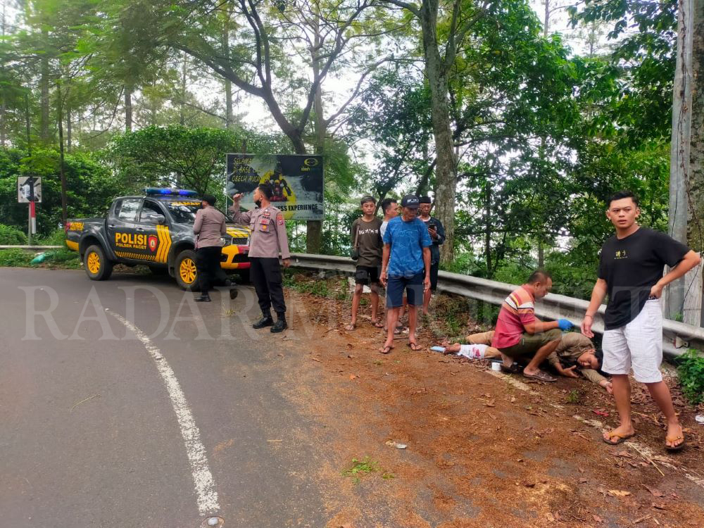 PENANGANAN: Petugas Polsek Pacet dibantu relawan memberikan pertolongan pertama pada korban.
