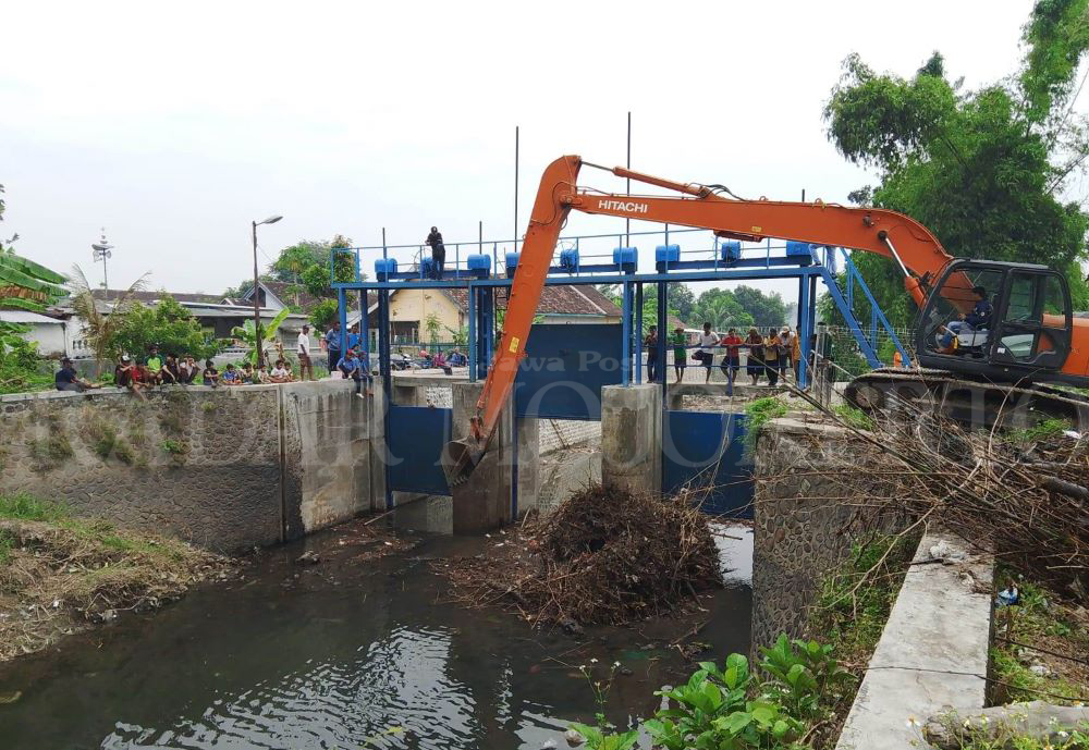 GERAK CEPAT: Dinas PUPR Kabupaten Mojokerto turunkan alat berat untuk pembersihan sumbatan sampah di Dam Desa Sadartengah, Kecamatan Mojoanyar, Minggu (23/6).&nbsp;