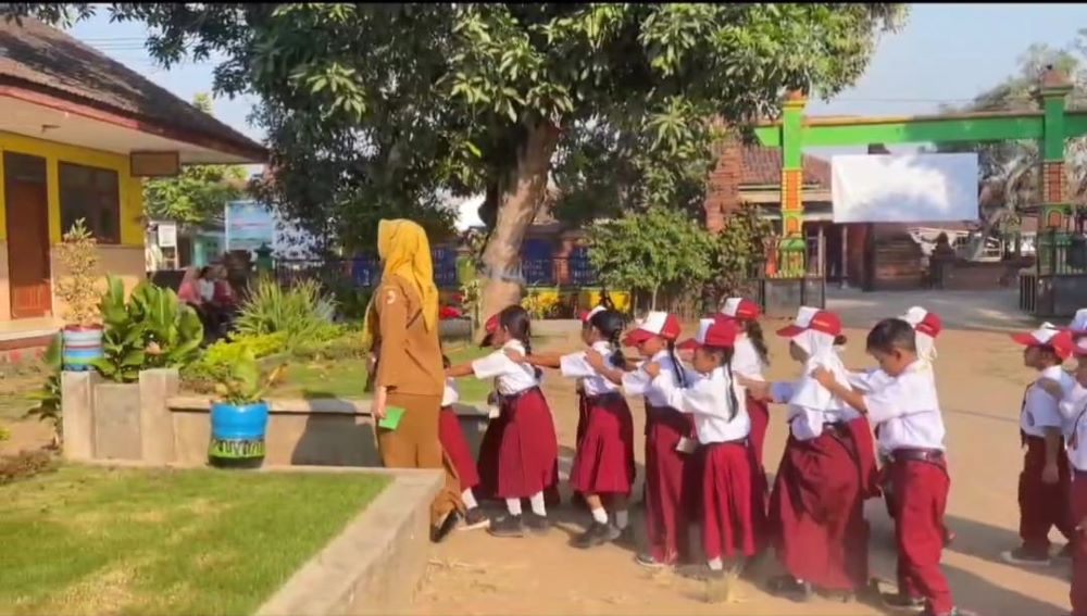 SERU: Guru membimbing siswa kelas 1 mengenal lingkungan sekolah dengan cara berbaris mengular.