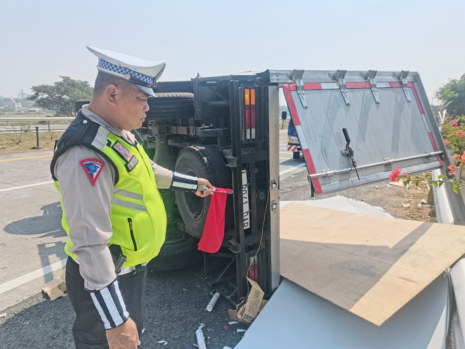 BERSERAKAN: Petugas PJR mengatur lalu lintas di lokasi tergulingnya truk boks bermuatan aluminium dan plafon di Tol Sumo KM 718, Desa Sidorejo, Kecamatan Jetis, kemarin (20/7).