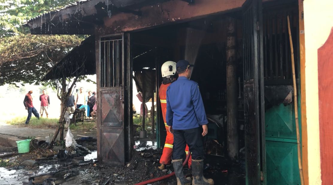 DIPADAMKAN: Petugas damkar memadamkan api yang melalap kios bensin eceran di Desa Ngimbangan, Mojosari, Selasa (23/7).
