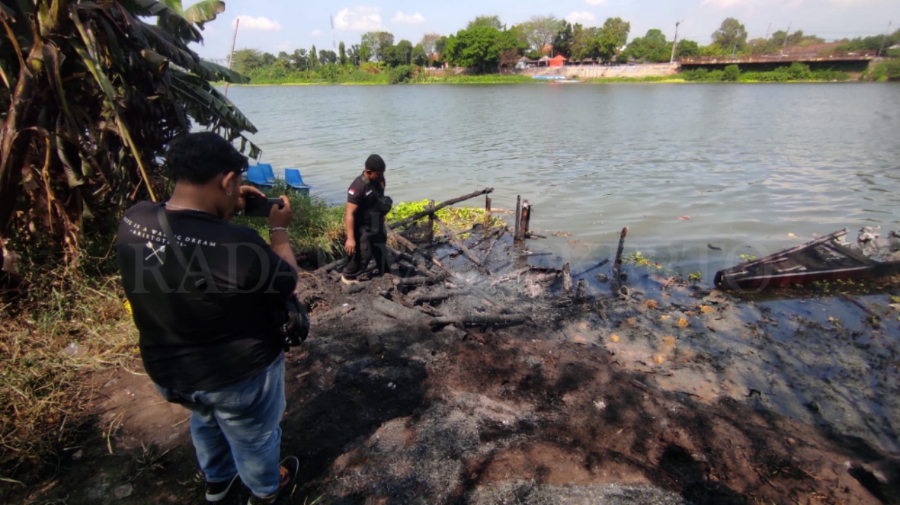 TINGGAL ABU: Atlet dayung bersama warga sekitar menyelamatkan puing-puing perahu naga milik Disbudporapar Kabupaten Mojokerto yang terbakar, Jumat (2/8).&nbsp;