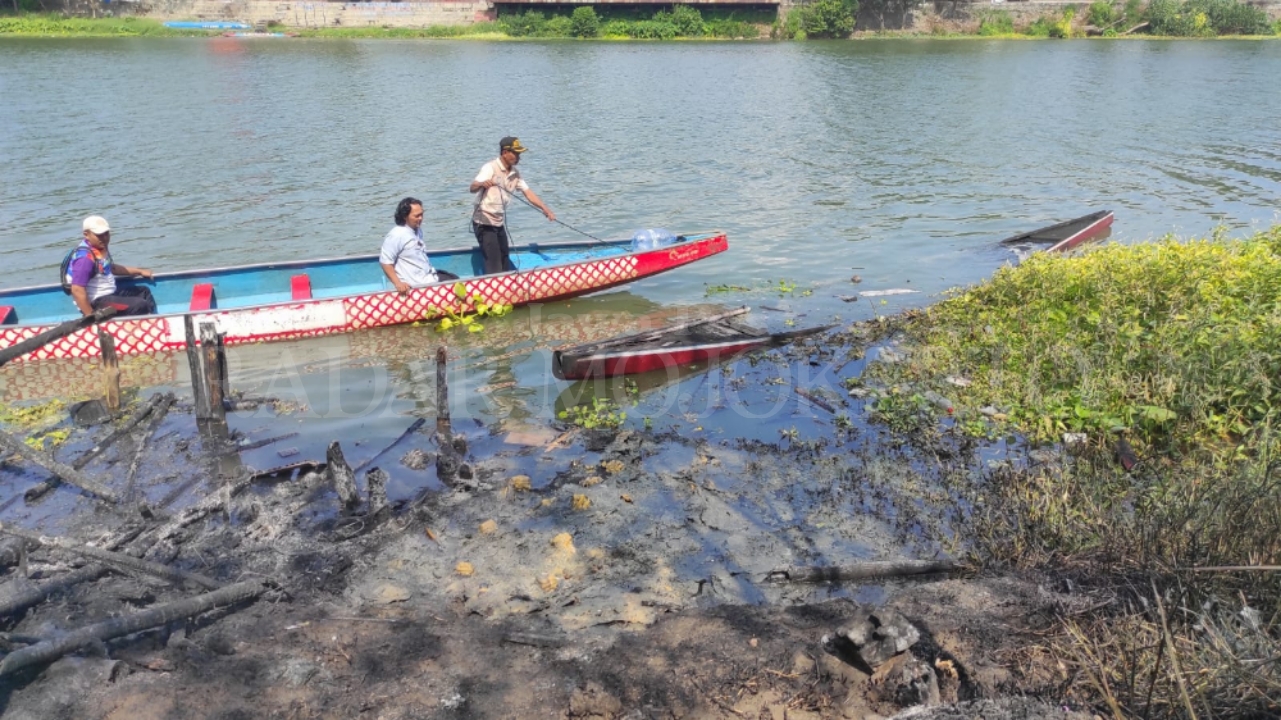 TINGGAL ABU: Atlet dayung bersama warga sekitar menyelamatkan puing-puing perahu naga milik Disbudporapar Kabupaten Mojokerto yang terbakar, Jumat (2/8).&nbsp;