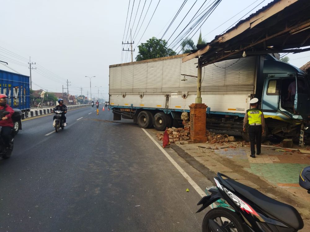 LAKA TUNGGAL: Petugas kepolisian mengamankan lokasi truk yang menabrak pagar rumah warga di Desa Jatipasar, Kecamatan Trowulan, Kabupaten Mojokerto, Jumat (2/8) dini hari.