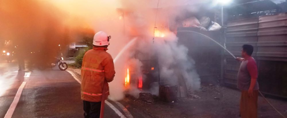 DISEMPROT: Petugas damkar memadamkan kobaran api yang melalap gudang rongsokan di Desa Jabon, Kecamatan Mojoanyar, Rabu (7/8) petang.