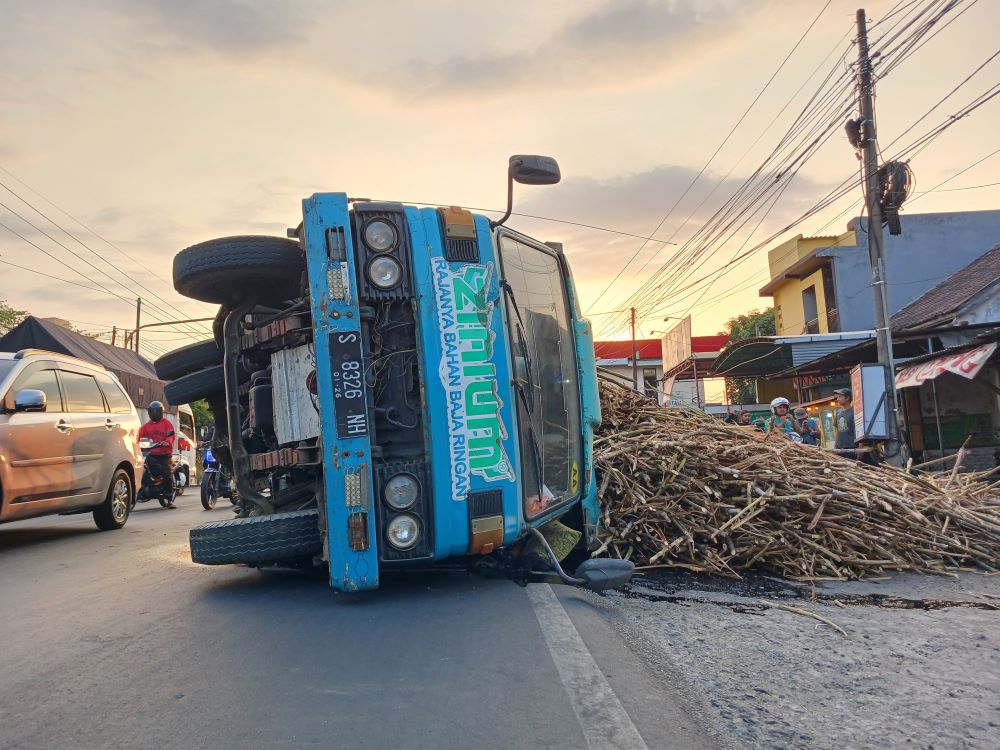 MENUTUP JALAN: Kondisi truk muatan tebu yang tergulir di Jalan Raya Desa Pacing, Kecamatan Bangsal, kemarin.