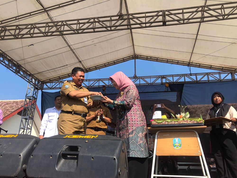 SIMBOLIS: Kepala Cabang Dinas Pendidikan Mudianto menyerahkan potongan tumpeng perayaan puncak HUT Ke-25 SMAN 1 Ngoro kepada Kepala SMAN 1 Ngoro Siti Arofah, kemarin (9/9).