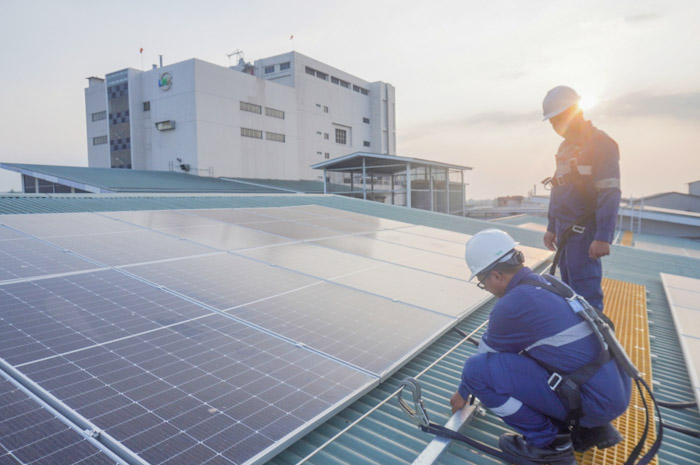RAMAH LINGKUNGAN: Pekerja memasang panel surya di atap gedung PT Lautan Natural Krimerindo untuk memenuhi kebutuhan energi.