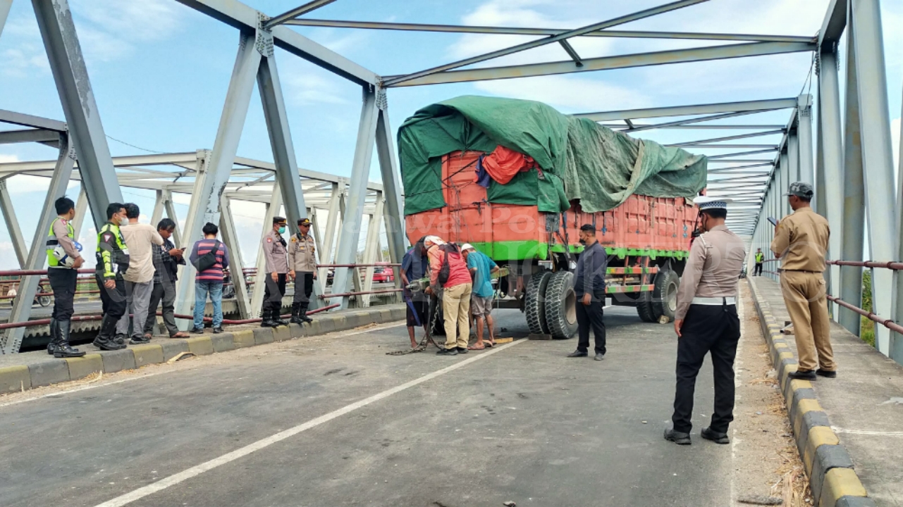 TUTUP BADAN JALAN: Petugas mengevakuasi gandengan truk yang nyungsep di sisi jembatan Kali Porong, Desa Ngrame, Kecamatan Pungging, Selasa (10/9).