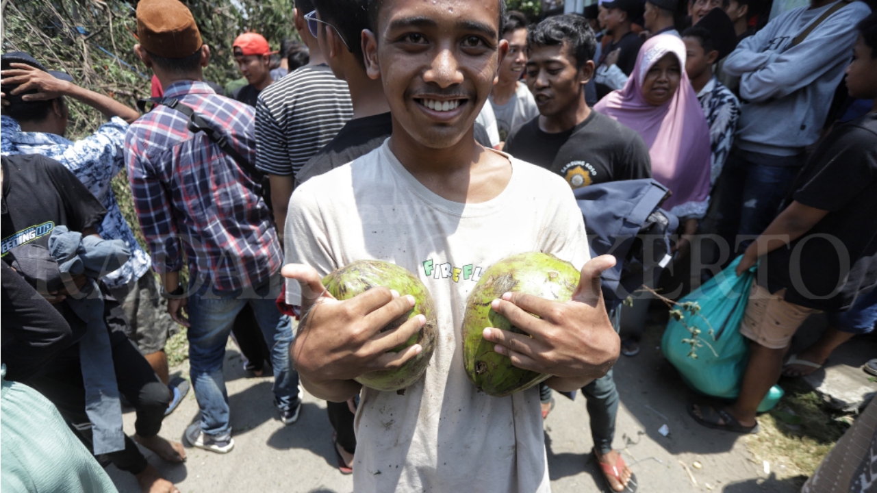 MERAKYAT: Pengunjung menunjukkan kelapa yang didapat saat mengikuti tradisi Keresan.