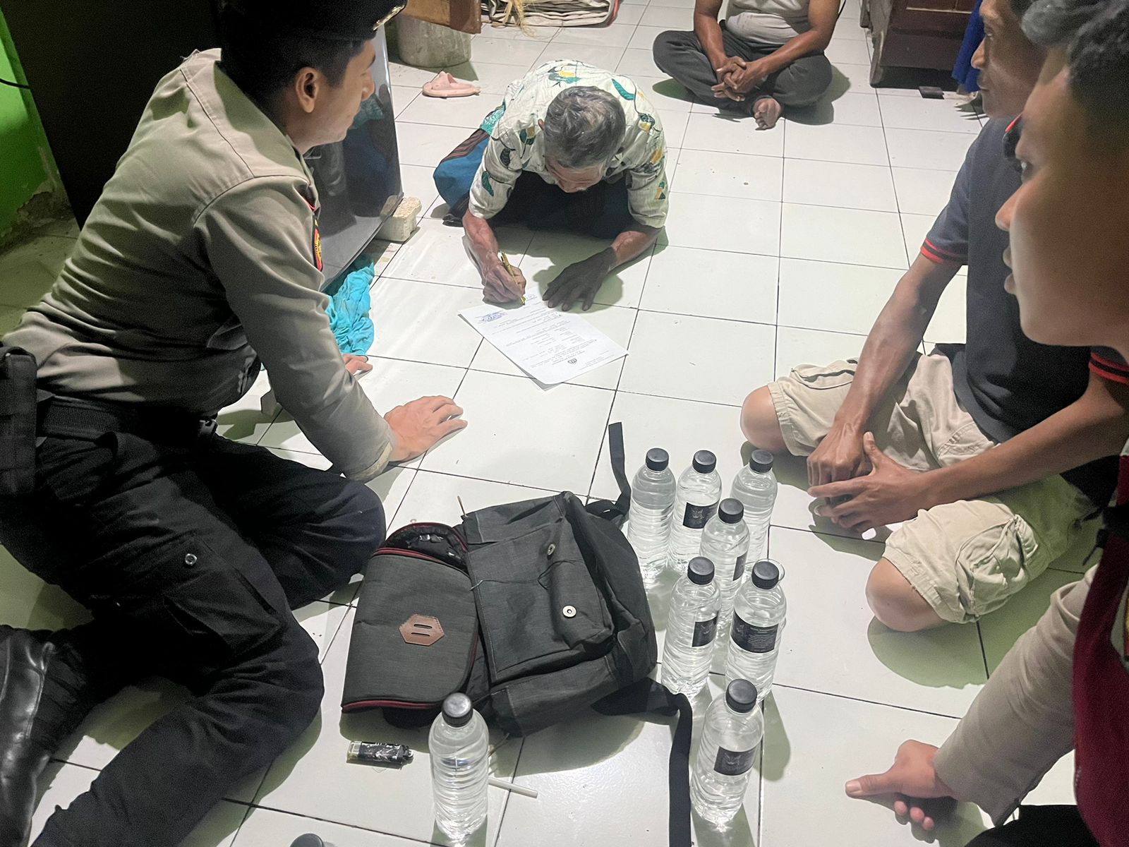 SITA BARANG BUKTI: Petugas Sat Samapta Polres Mojokerto mengamankan puluhan botol miras jenis arak bali hasil penertiban, Selasa (17/9) malam.