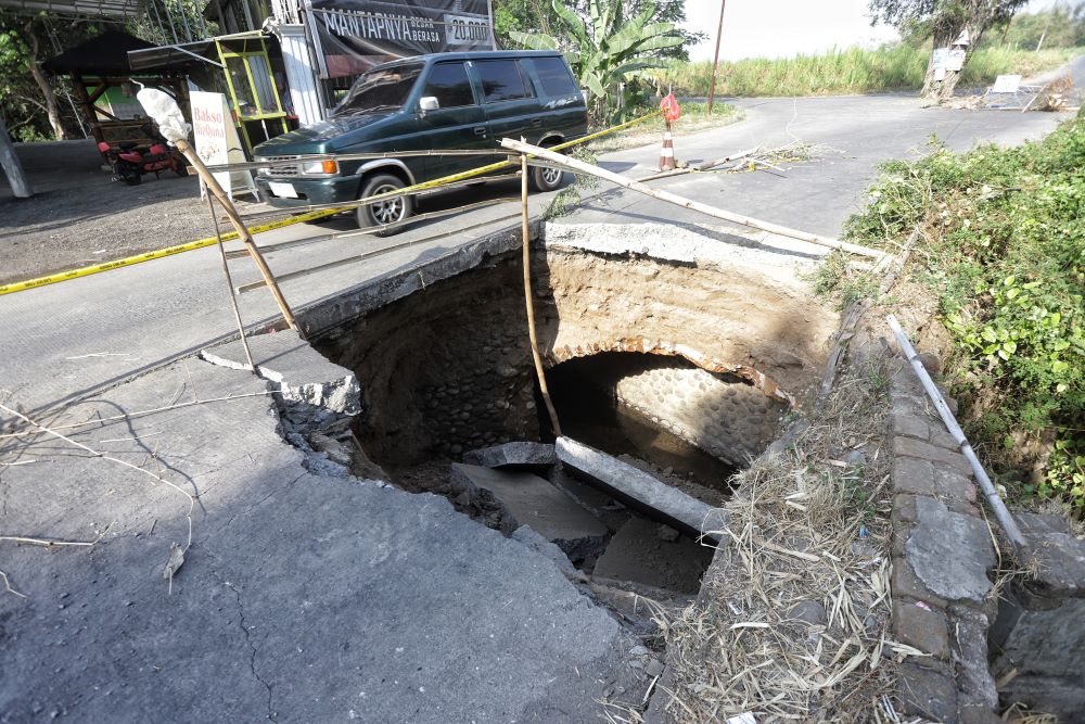 MENGANGA: Pengendara melintasi Jalan Raya Desa Karangjeruk, Kecamatan Jatirejo, yang mendadak ambles sedalam 2 meter, Kamis (19/9).