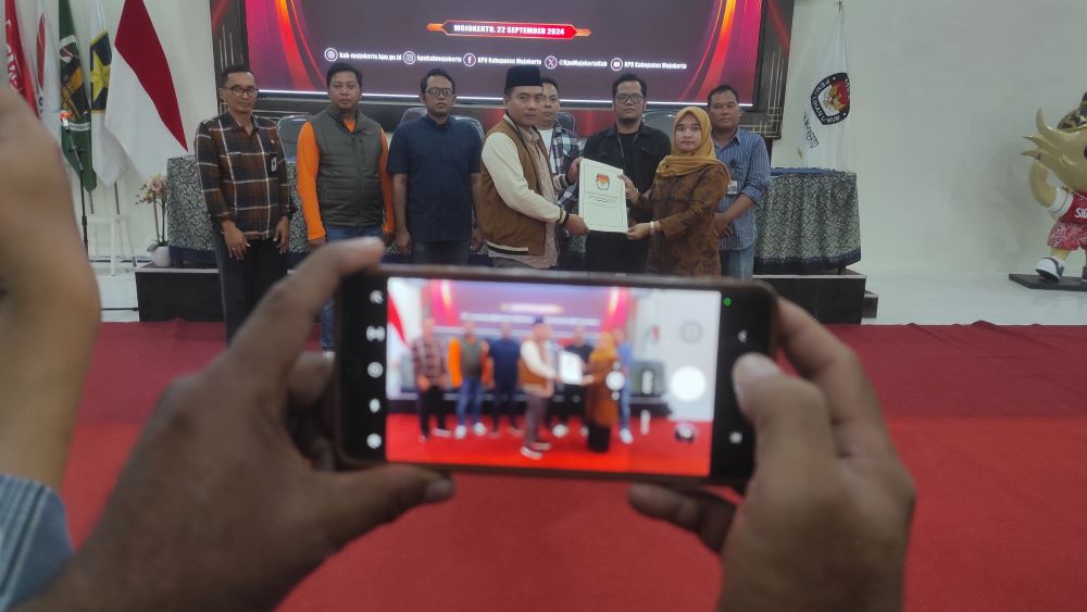 SIAP BERTARUNG: Ketua KPU Kabupaten Mojokerto, Afnan Hidayat bersama seluruh komisioner dan bawaslu memberikan pernyataan hasil pleno penetapan paslon di gedung KPU, Jalan R.A.A.K Adinegoro Sooko.