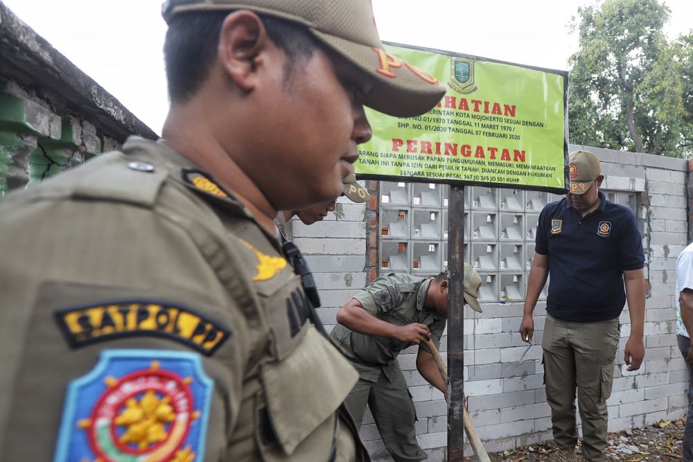 PERINGATAN: Petugas Satpol PP Kota Mojokerto bersama aparat gabungan memasang papan tanda aset Pemkot Mojokerto di atas lahan di Kelurahan/Kecamatan Kranggan, kemarin (27/9).