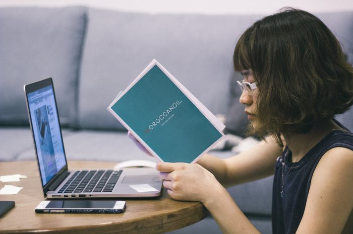 Terlihat seorang yang tengah duduk sendiri yang sedang fokus kerja dan membaca buku.