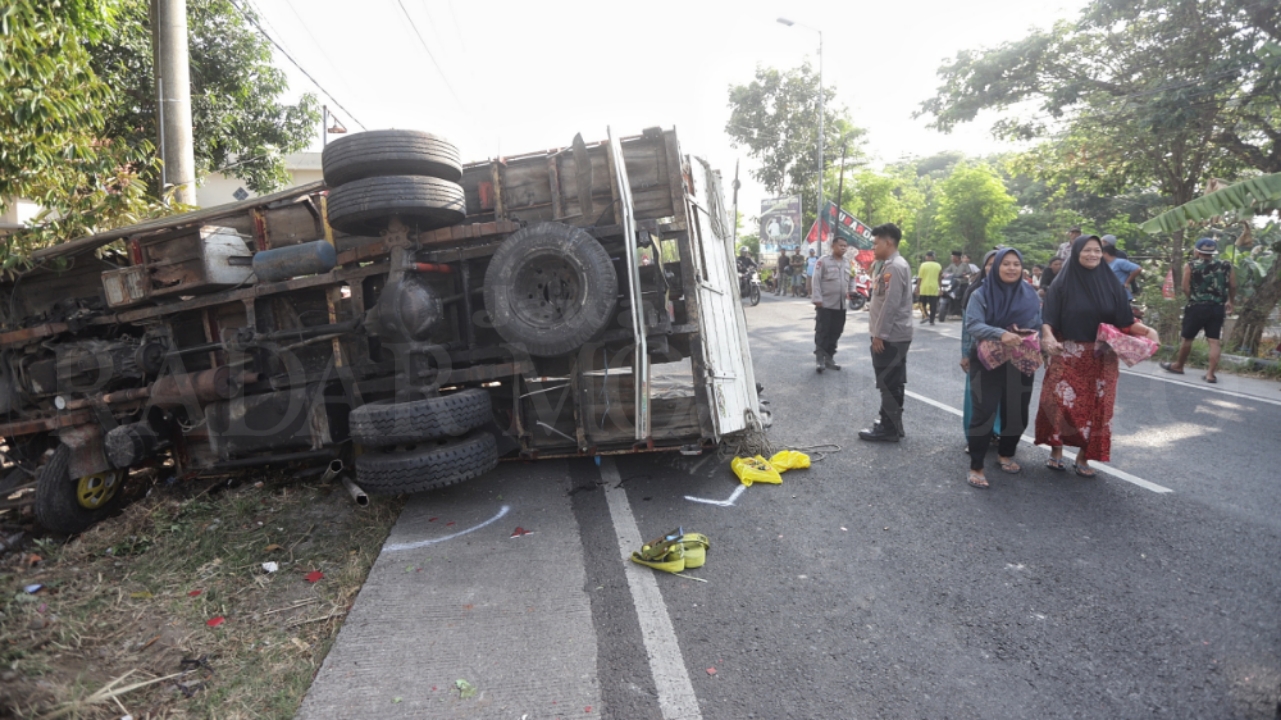 TRUK NAHAS: Bangkai truk usai menabrak dua perempuan di Jalan Raya Desa Bandung, Kecamatan Gedeg, tampak terguling didekatnya dua polisi berjaga, Selasa (8/10).