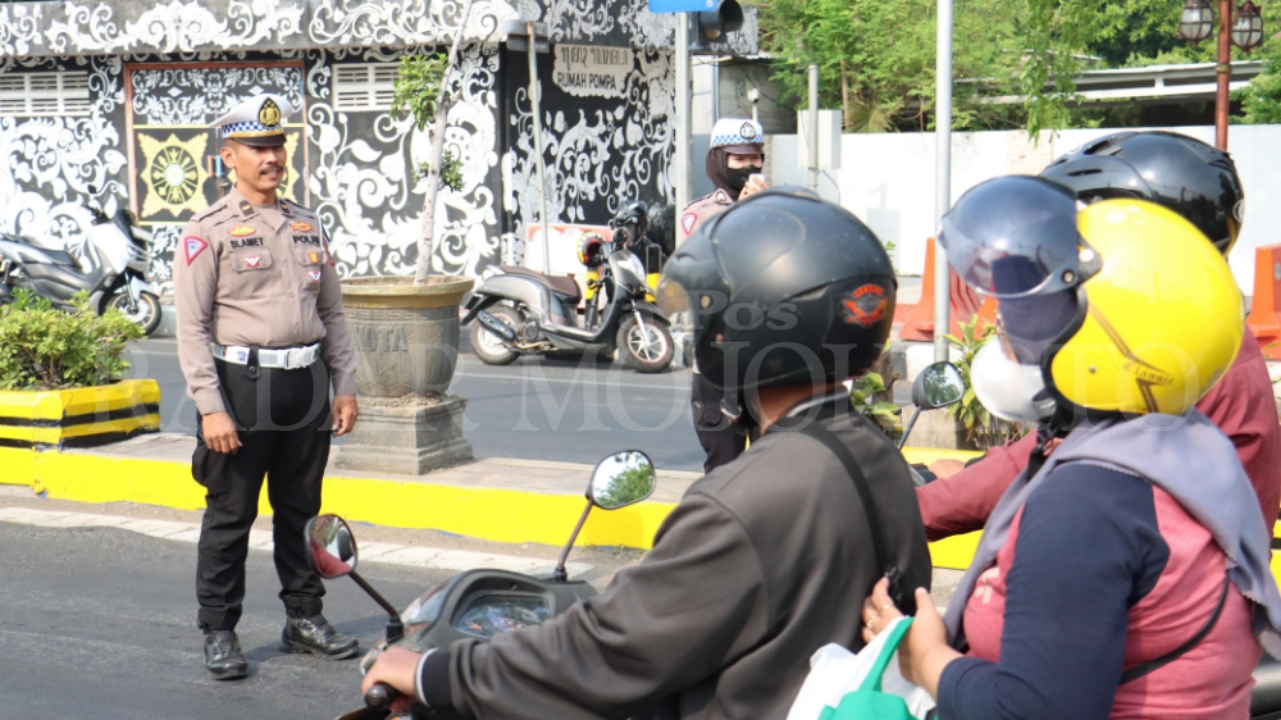 EDUKASI: Petugas Polres Mojokerto Kota menyampaikan edukasi kepada pengendara lalu lintas di Simpang Tropodo, Selasa (15/10).