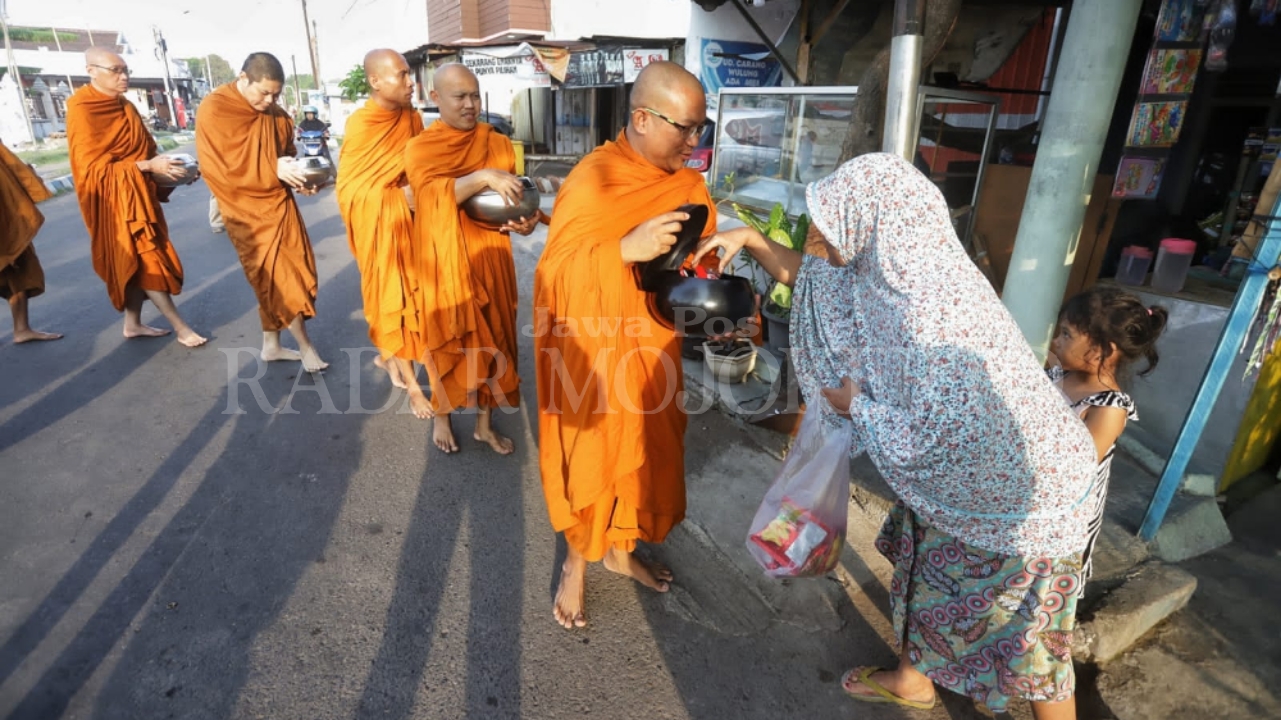 Umat Muslim turut berderma kepada biksu saat prosesi pindapatta di Magersari Kota Mojokerto, Minggu (20/10).