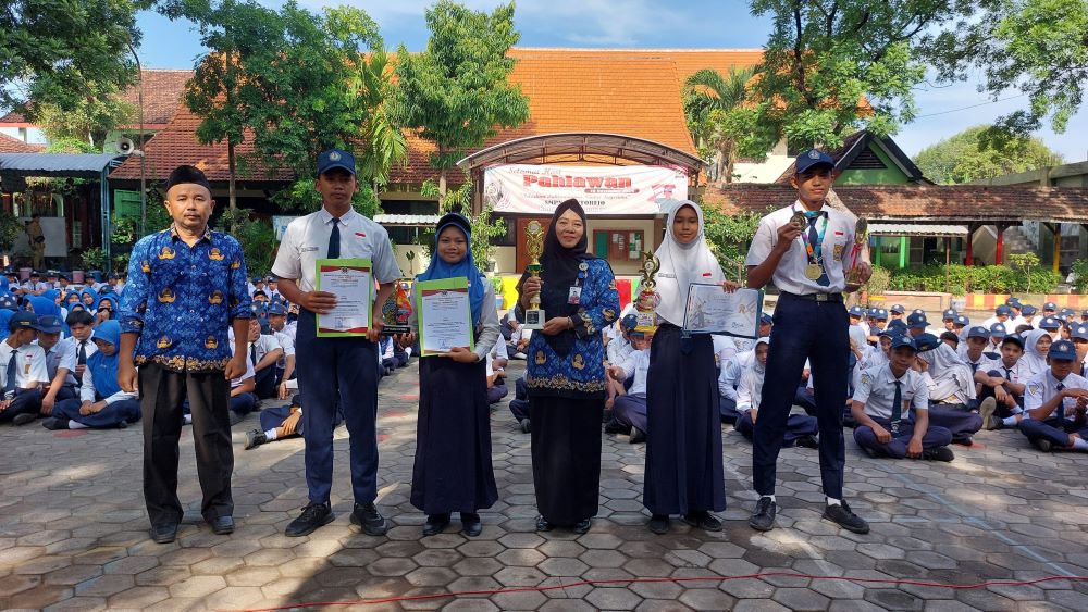 BENTUK APRESIASI: Kepala SMPN 2 Kutorejo menyerahkan penghargaan kepada siswa berprestasi.