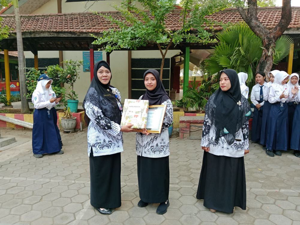 BERDEDIKASI: Kepala SMPN 2 Kutorejo Rahayu Wijayati memberikan penghargaan pada guru dan tenaga kependidikan yang berprestasi usai upacara, Senin (25/11).
