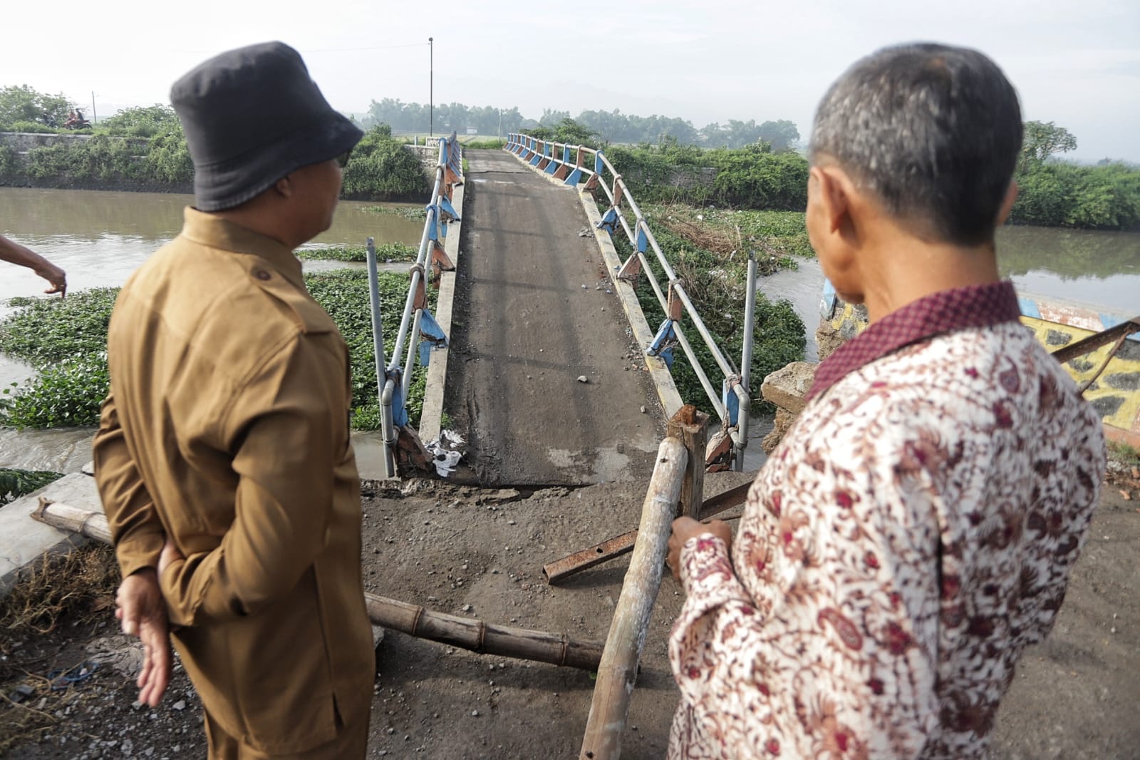 DITERJANG: Perangkat desa setempat melihat kerusakan jembatan.