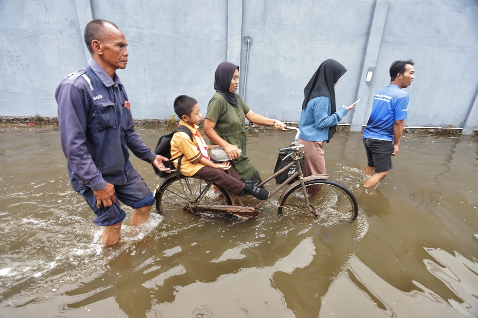 TERDAMPAK: Sejumlah warga melintasi jalan yang terendam banjir di Desa Salen, Kecamatan Bangsal, Kabupaten Mojokerto, Jumat (6/12/2024).