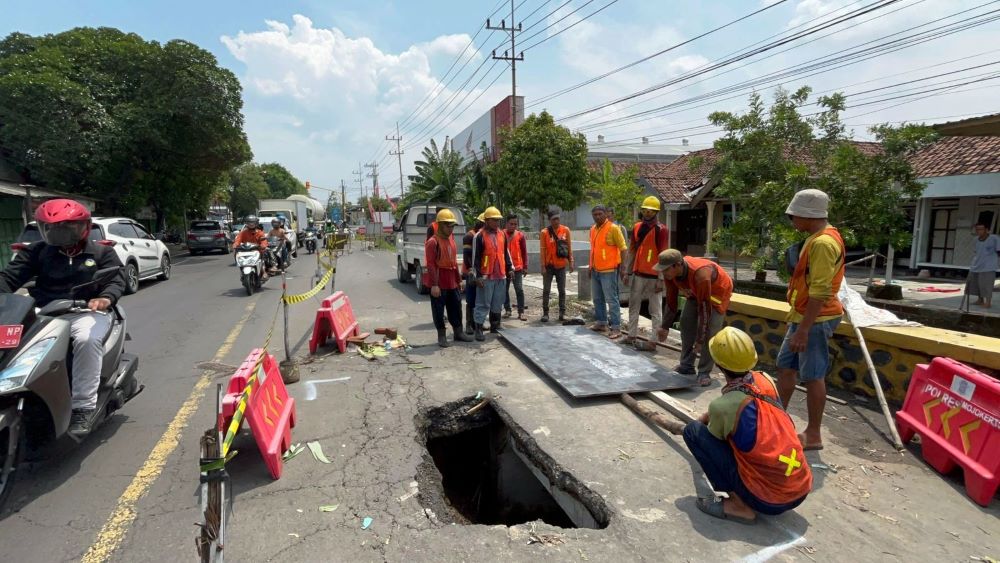 PERBAIKAN: Sejumlah petugas memasang pelat baja pada bagian Jalan Raya Mojokerto-Pasuruan, Desa Tawangsari, Kecamatan Bangsal, Kabupaten Mojokerto, Kamis (12/12).