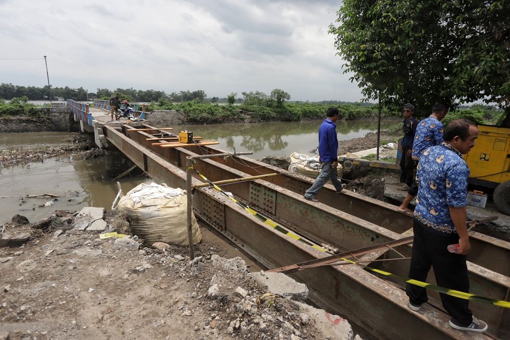 DIKEBUT: Dinas PUPR Kabupaten Mojokerto membuat jembatan darurat dengan memasang besi WF sebagai konstruksi utama jembatan di Desa Kedunggempol, Kecamatan Mojosari, kemarin (17/12).