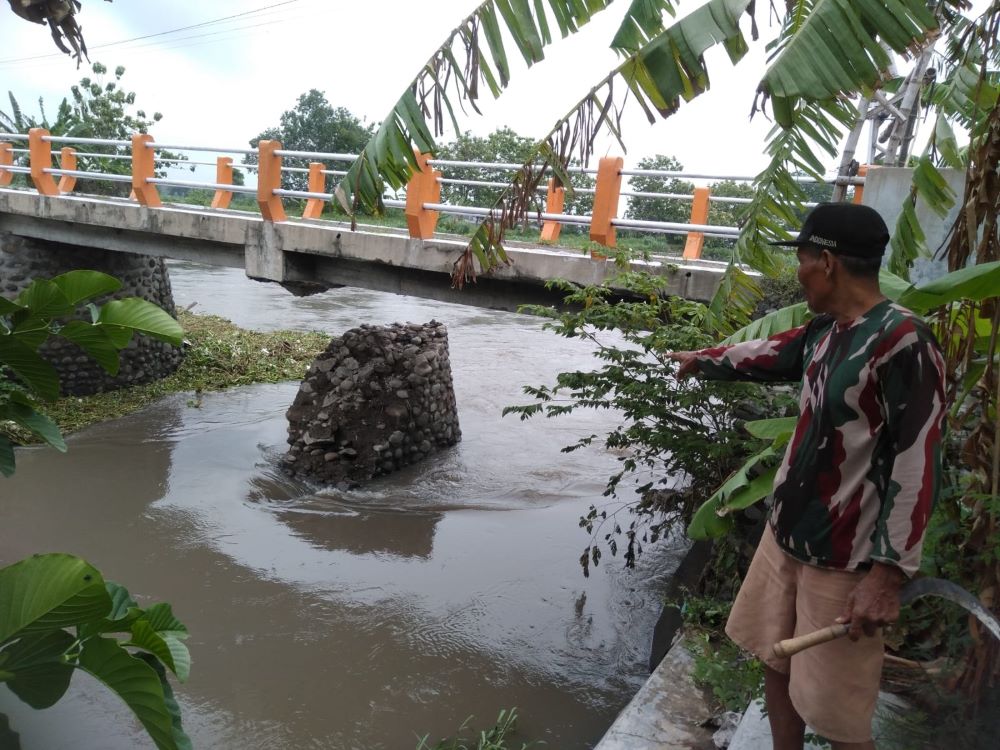 DITUTUP: Warga menunjukkan fondasi penyangga Jembatan Desa Balongmasin, Kecamatan Pungging, yang putus akibat diterjang banjir.