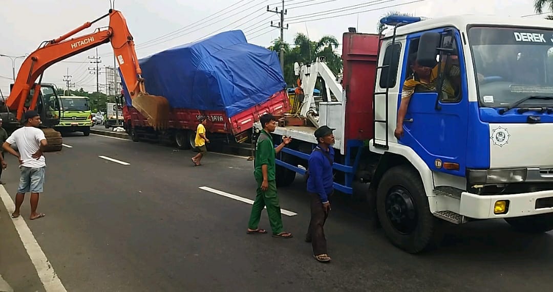 EVAKUASI: Dua alat berat tampak mengevakuasi truk tronton yang naik median jalan di ruas jalan Nasional Mojokerto-Mojoagung, simpang tiga Jampirogo, Sooko, Kabupaten Mojokerto, Senin (7/1/2025).