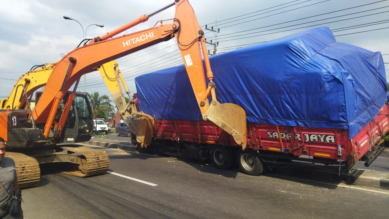 EVAKUASI: Dua alat berat tampak mengevakuasi truk tronton yang naik median jalan di ruas jalan Nasional Mojokerto-Mojoagung, simpang tiga Jampirogo, Sooko, Kabupaten Mojokerto, Senin (7/1/2025).