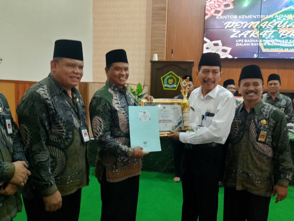 MODERAT: Kepala Kementerian Agama Kabupaten Mojokerto Muttakin menyerahkan penghargaan kepada Kepala SMAN 1 Sooko Sutoyo saat resepsi Hari Amal Bhakti Kemenag ke 79 di aula Kemenag Kabupaten Mojokerto