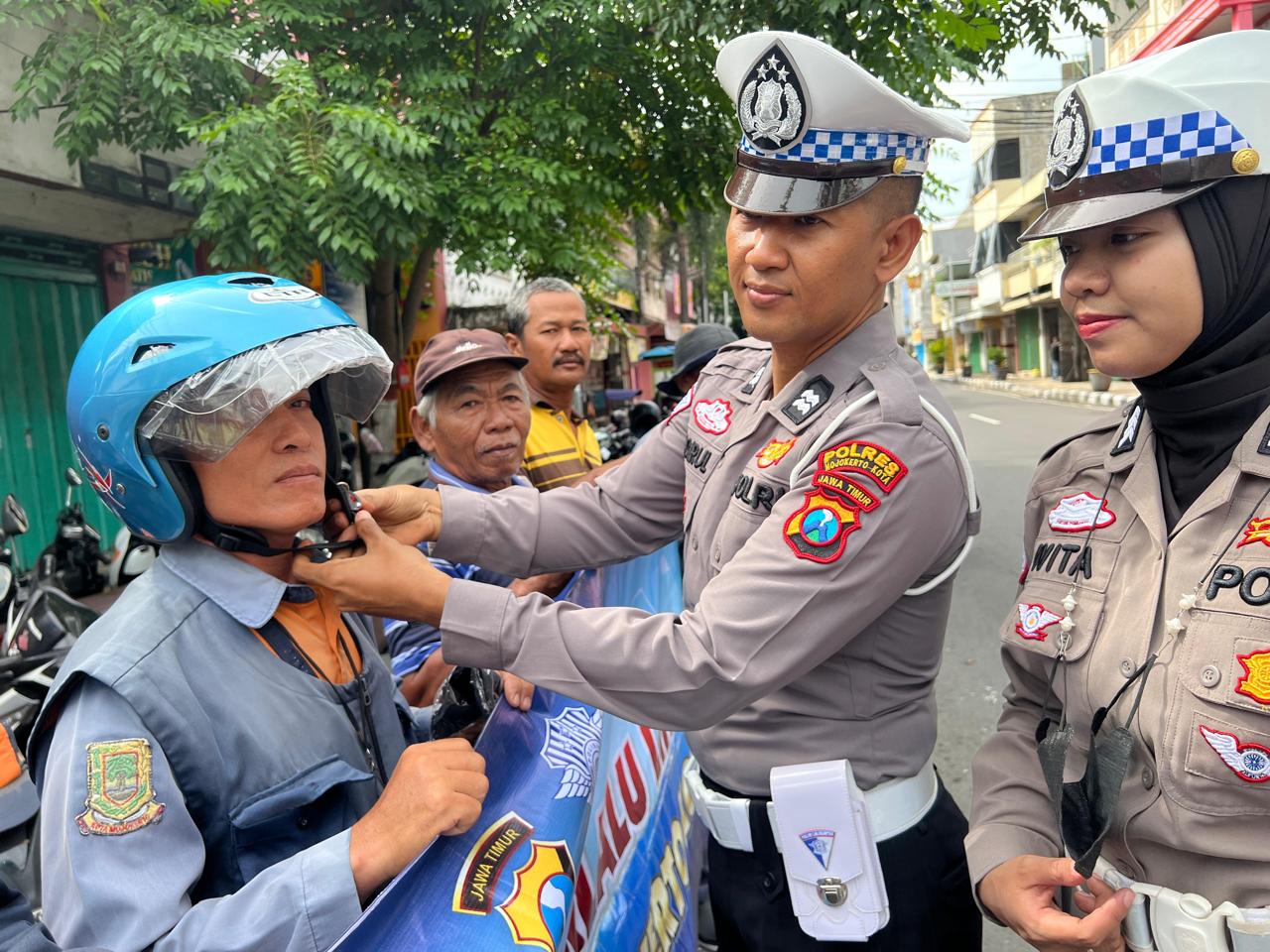SINERGI: Petugas Satlantas Polres Mojokerto Kota mengenakan helm kepada jukir.