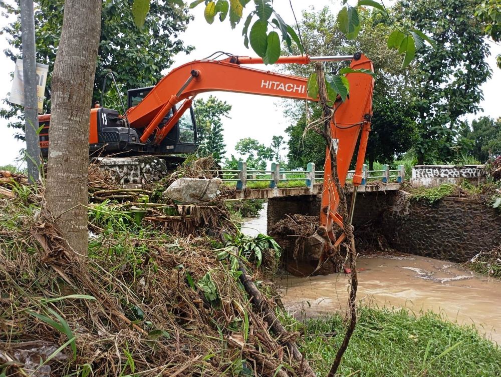 PENANGGULANGAN: Alat berat milik DPUPR Kabupaten Mojokerto mengangkut sampah dan sedimentasi yang meyumbat aliran Kali Putih, Dusun Bancang, Desa Pakis, Kecamatan Trowulan, Senin (20/1).