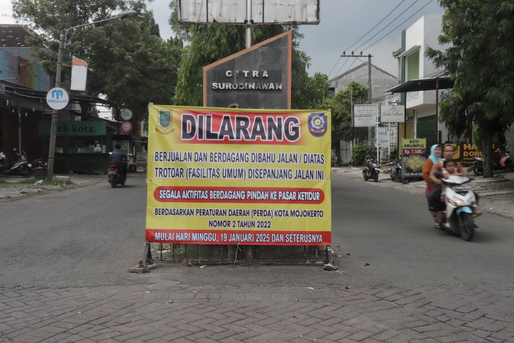 DIPINDAH: Pengumuman larangan berjualan bagi PKL terpasang di akses masuk Jalan Citra Surodinawan Estate, Kelurahan Surodinawan, Kecamatan Prajurit Kulon, Kota Mojokerto.