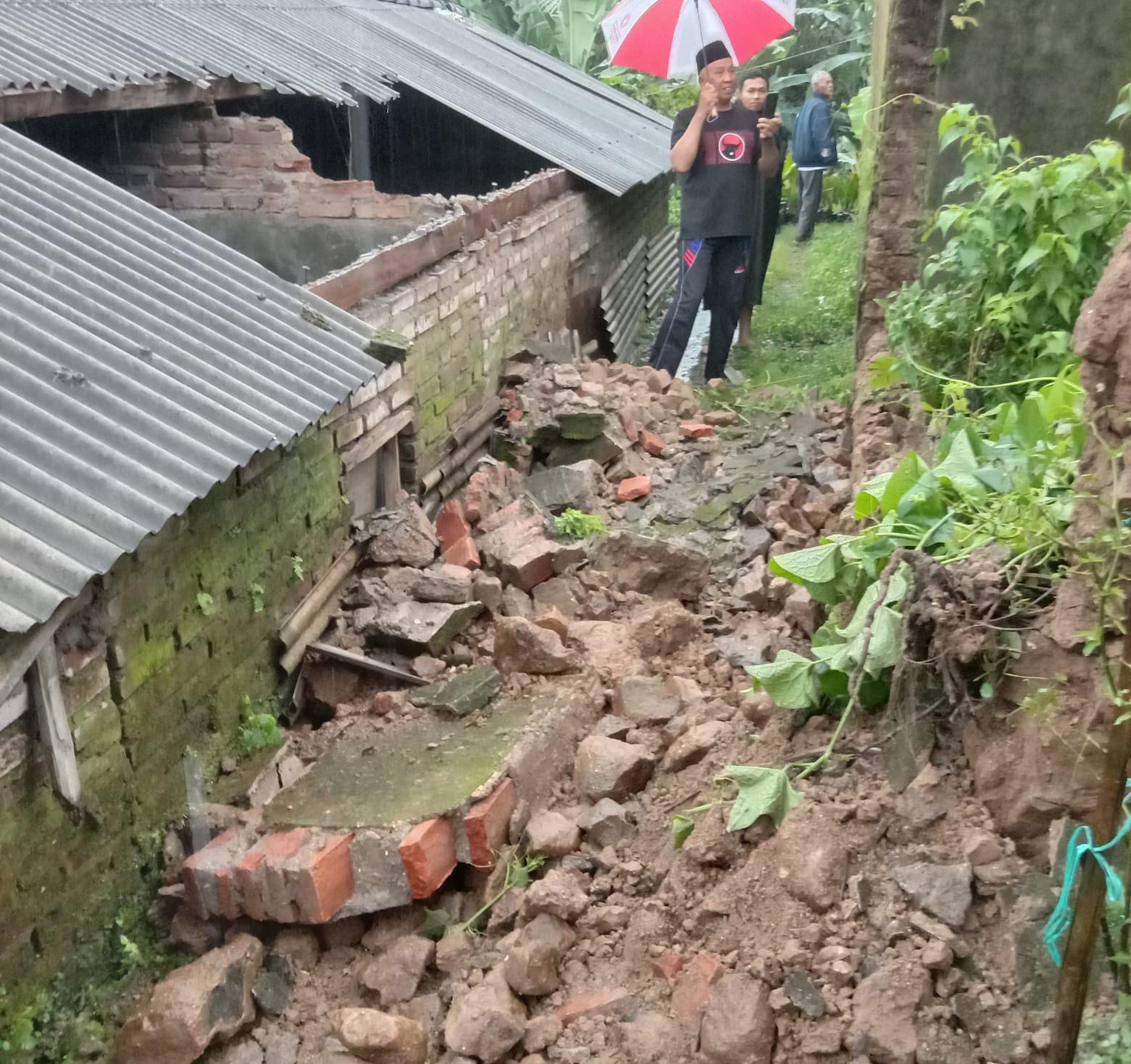TELAN KORBAN: Kondisi rumah usai tertimpa tembok runtuh di Desa Cembor, Kecamatan Pacet, ambruk menimpa rumah di sampingnya, Kamis (23/1) sore.