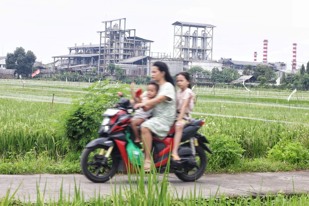 TIMBULKAN BAU BUSUK: Warga melintas di dekat pabrik pengolahan bioetanol PT Enero di Desa Gempolkrep, Kecamatan Gedeg, yang diduga tidak ramah lingkungan.