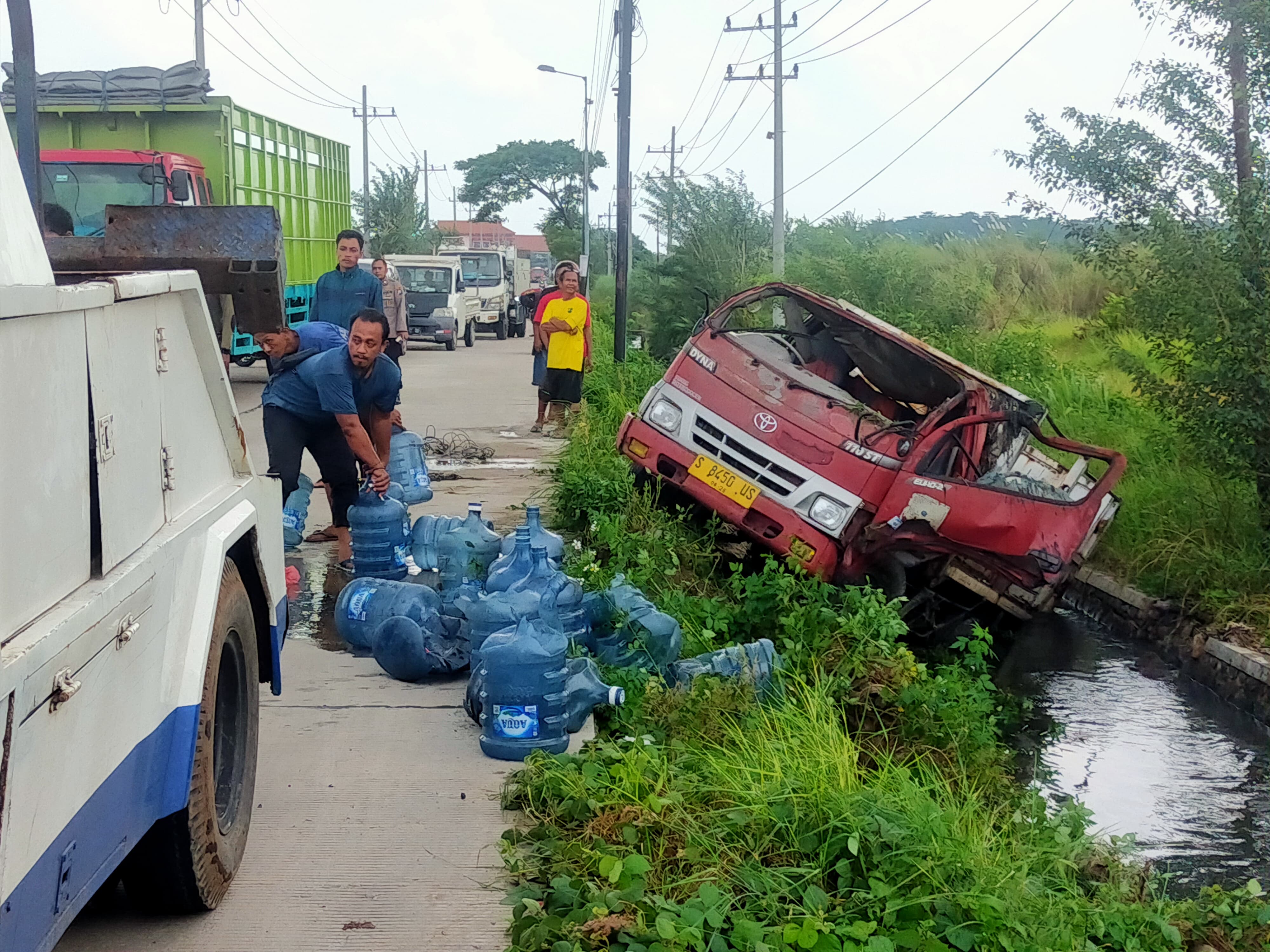 DIDEREK: Truk muatan air mineral galon merek Aqua nyungsep di parit Desa Ngarjo, Kecamatan Mojoanyar, Selasa (4/2) siang.